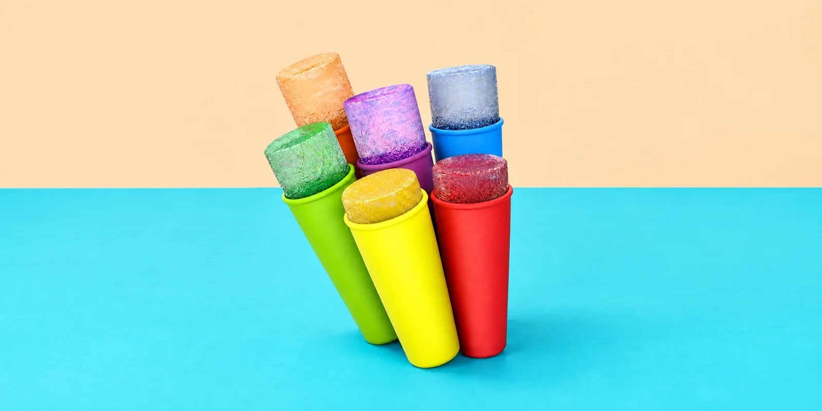 Colourblocker ice-pop moulds in six colours against a peach and turquoise studio background